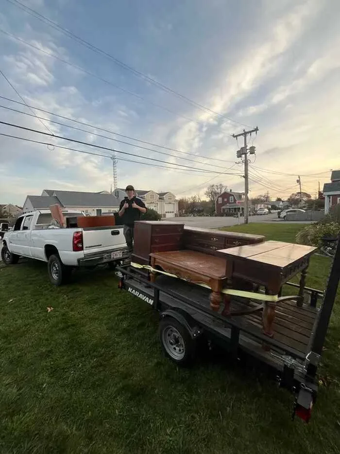 White pickup with a trailer carrying furniture at dusk